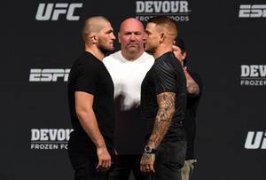 兩名男性MMA拳手在UFC稱重儀式上由裁判隔開，互相對峙。 — 終極格鬥冠軍賽 壁紙