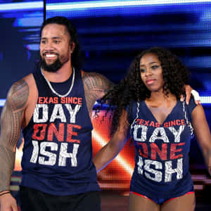 兩名職業摔角手穿著相配的德州主題背心在舞台上擺姿勢。 — WWE GIF 壁紙