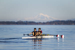 兩個人在湖上划船，背景是積雪覆蓋的山峰。 — 划船 壁紙