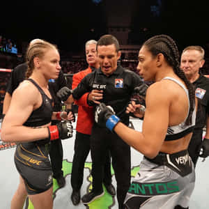 兩名女性MMA拳手以戰鬥姿勢在UFC八角籠中面對面，裁判在旁。 — 終極格鬥冠軍賽 壁紙