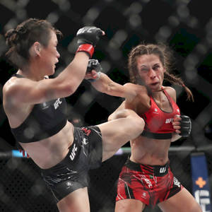兩名身穿UFC裝備的女性拳手在八角籠內交換高踢和格擋。 — 運動 壁紙