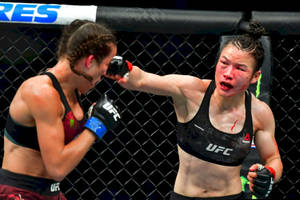 兩名女性拳手在UFC八角籠比賽中互相出拳，可見血跡。 — 運動 壁紙