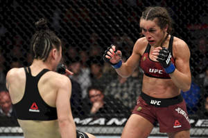 UFC比賽中，兩名女性拳手在籠內，一人前衝。 — 運動 壁紙