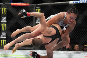 兩名女子MMA拳手在八角籠內進行動態抱摔。 — 酷 壁紙