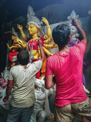 工匠在工作室中繪畫色彩繽紛的印度教女神雕像。 — Maa Durga 壁紙