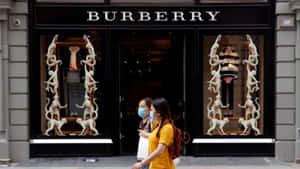 兩名戴著口罩的女性經過一間Burberry商店，櫥窗內有猴子雕塑。 — Burberry 壁紙