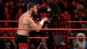 兩名摔角手在摔角擂台上對峙，背景有觀眾。 — WWE GIF 壁紙