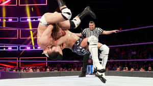 比賽中摔角手在半空中，背景有裁判和觀眾。 — WWE GIF 壁紙