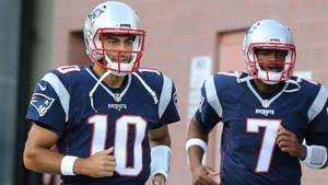 兩名NFL美式足球員在練習時穿著愛國者隊制服慢跑。 — 16:9 壁紙
