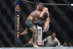 兩名男性MMA拳手在UFC比賽期間於八角籠內纏鬥。 — 中性 壁紙