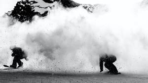 兩名滑雪板手在白雪覆蓋的山坡上滑下，掀起巨大的雪花。 — 雪山 壁紙