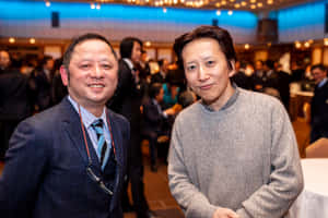 兩名男子在室內社交聚會中擺姿勢拍照。 — 阿基拉 壁紙