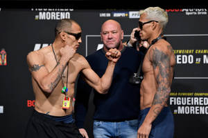 兩名肌肉發達的紋身拳手在稱重時與裁判鎖拳。 — 終極格鬥冠軍賽 壁紙