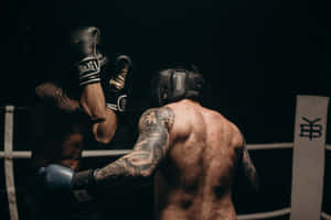 兩名紋身拳擊手在擂台上於昏暗燈光下互相出拳。 — 拳擊 壁紙