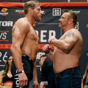 兩名赤裸上身的男性MMA拳手在稱重儀式中握拳對峙，氣氛緊張。 — 運動 壁紙