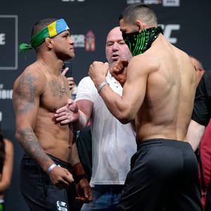 兩名赤裸上身的MMA拳手在比賽前互相瞪視，中間有裁判。 — 終極格鬥冠軍賽 壁紙