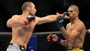 兩名MMA拳手在UFC八角籠中比賽時互相出拳。 — Alex Pereira 壁紙