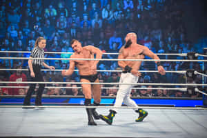 兩名摔角手在擂台上，有裁判和歡呼的觀眾。 — WWE GIF 壁紙