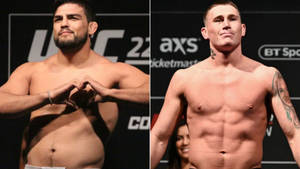 兩名赤裸上身的男性MMA拳手在稱重時，一人做出心形手勢，另一人自信站立。 — 1600x900 壁紙