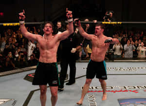 兩名筋疲力盡的MMA拳手在UFC八角籠內與歡呼的粉絲一起慶祝勝利。 — 終極格鬥冠軍賽 壁紙
