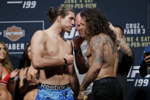 兩名MMA拳手在UFC過磅活動中，背景有粉絲和標誌，互相凝視。 — 3:2 壁紙