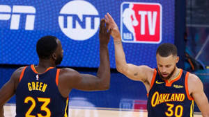 兩名NBA籃球運動員在比賽中擊掌。 — 史蒂芬·柯瑞 壁紙