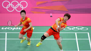 兩名身穿紅色球衣的女羽球選手在綠色球場上競爭。 — 羽球 壁紙