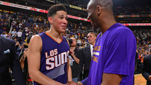 兩名籃球運動員在比賽期間在球場上握手。 — Devin Booker 壁紙