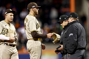 棒球運動員和裁判在夜間燈光球場上互動。 — MLB 壁紙
