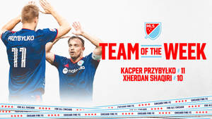 兩名身穿藍色球衣的足球運動員慶祝，帶有「Team of the Week」文字和芝加哥火焰FC品牌標誌。 — 運動 壁紙