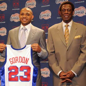 兩名身穿西裝的男子，其中一人手持一件帶有Gordon名字和23號的快艇隊球衣 — 美學科比 壁紙