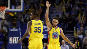 兩名身穿黃色球衣的NBA籃球運動員高舉雙手慶祝一次進攻。 — 史蒂芬·柯瑞 壁紙