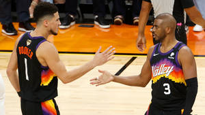 兩名籃球運動員在比賽中在球場上握手。 — Devin Booker 壁紙