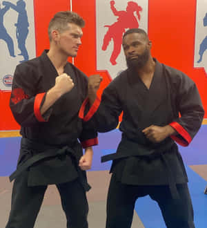 兩名身穿武術制服的男人在訓練軟墊上擺出戰鬥姿勢。 — 榮耀Magic V Flip 2 壁紙