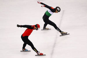 兩名速度滑冰選手在溜冰場上比賽，一人身穿紅色中國隊裝備，另一人身穿綠色、白色、黑色裝備，號碼10。 — 運動 壁紙
