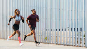兩人在陽光明媚的日子裡在高金屬圍欄附近慢跑。 — Running 壁紙