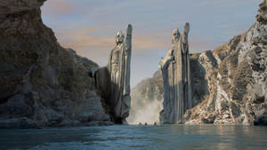 峽谷中兩座高聳的雕像俯瞰著河流上的小船。 — Lotr 壁紙