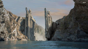峽谷中兩座高聳的石像，旁邊有河流和小船。 — Lotr 壁紙