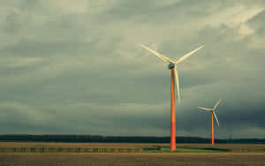 黃昏時分，陰天下田野中的兩座風力發電機。 — 2880x1800 壁紙