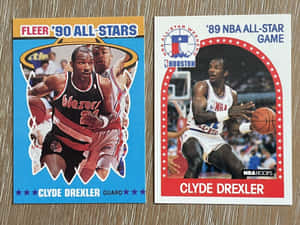 兩張 1980 年代 Clyde Drexler 的 NBA 全明星交換卡在木頭上。 — 運動 壁紙