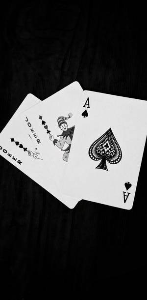 兩張撲克牌，一張黑桃A和一張Joker，在深色木頭上。 — 黑白小丑 壁紙