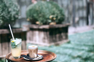 花園環境中木托盤上的兩杯飲品，背景柔和模糊。 — MacBook Air 壁紙