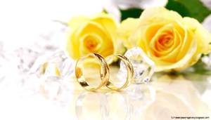 兩枚帶有葉紋設計的金色結婚戒指，旁邊有黃玫瑰和透明水晶。