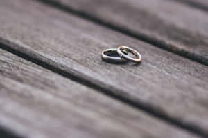 兩枚結婚戒指一起放在木桌上。 — 結婚戒指 壁紙