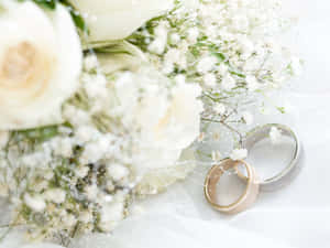 兩枚結婚戒指放在白色花束旁邊，布料透薄。 — 結婚戒指 壁紙