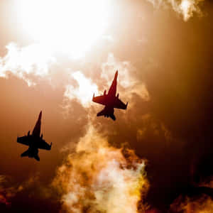 兩架戰鬥機以剪影飛過充滿活力的日落天空。 — 空軍 壁紙