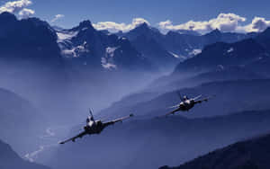 兩架戰鬥機飛越有雪峰和霧谷的山脈。 — 航太 壁紙