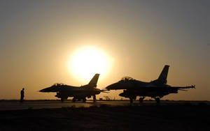 機場上夕陽映襯下的兩架戰鬥機剪影。 — 獵鷹 壁紙