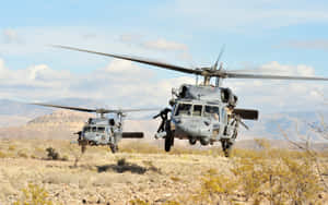 兩架軍用直升機低空飛越沙漠，背景有山脈。 — 藍天 壁紙