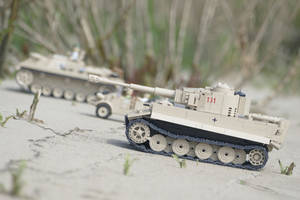 兩架米色LEGO軍用坦克在沙地上，伴有乾草。